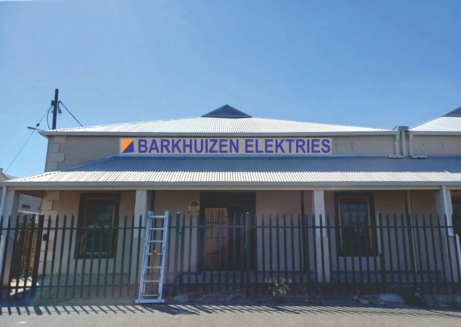 Barkhuizen Elektries building exterior with blue ladder leaning against fenced entrance.