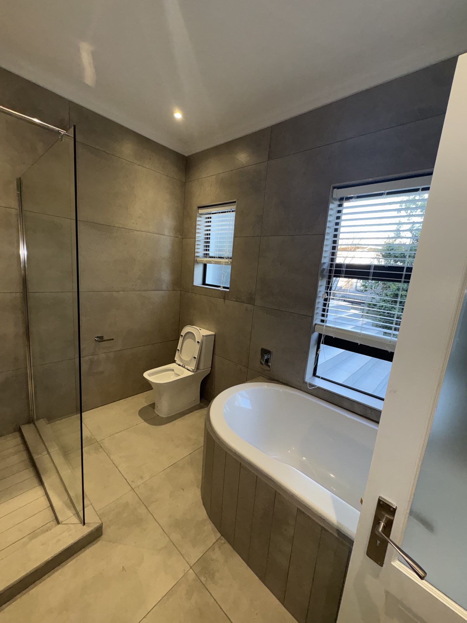Luxury bathroom with freestanding tub, large walk-in shower with glass enclosure, and neutral tile finishes.