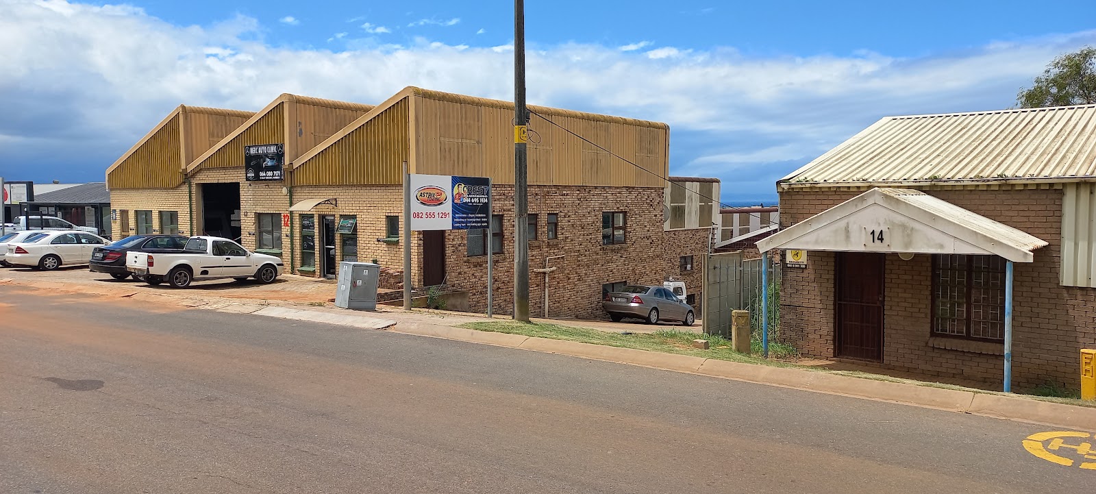 Industrial brick workshop facility with parked vehicles and "Crest" signage visible on storefront.