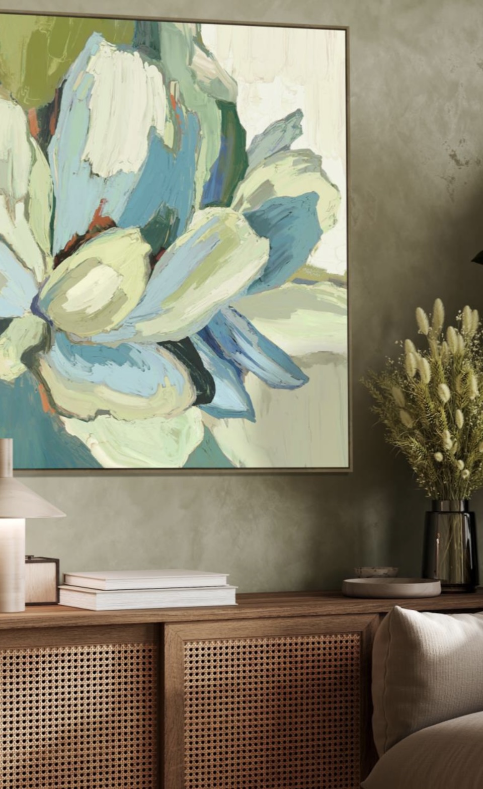 Styled shelf with abstract floral artwork, wooden furniture with rattan details, books, and dried flowers.