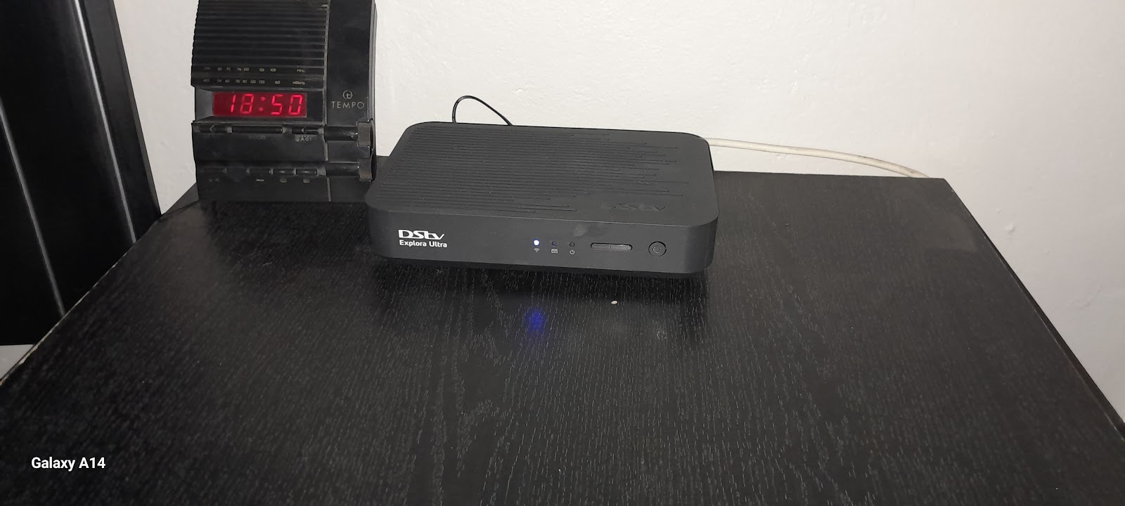 DStv Exploro Ultra decoder box on black table with vintage radio equipment.