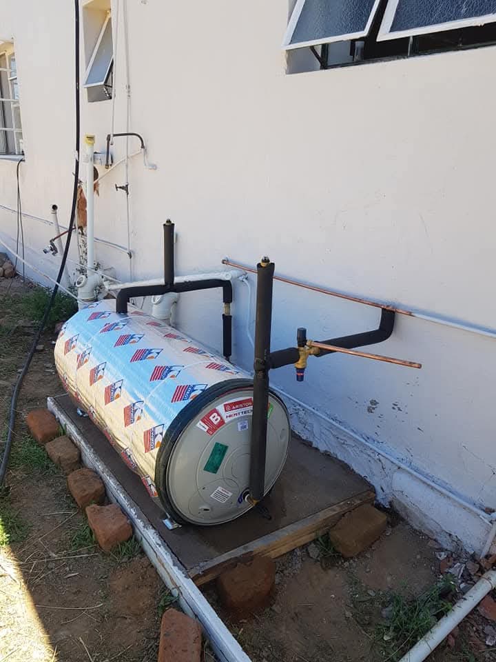 Gas cylinder and copper piping installation against residential property exterior wall.