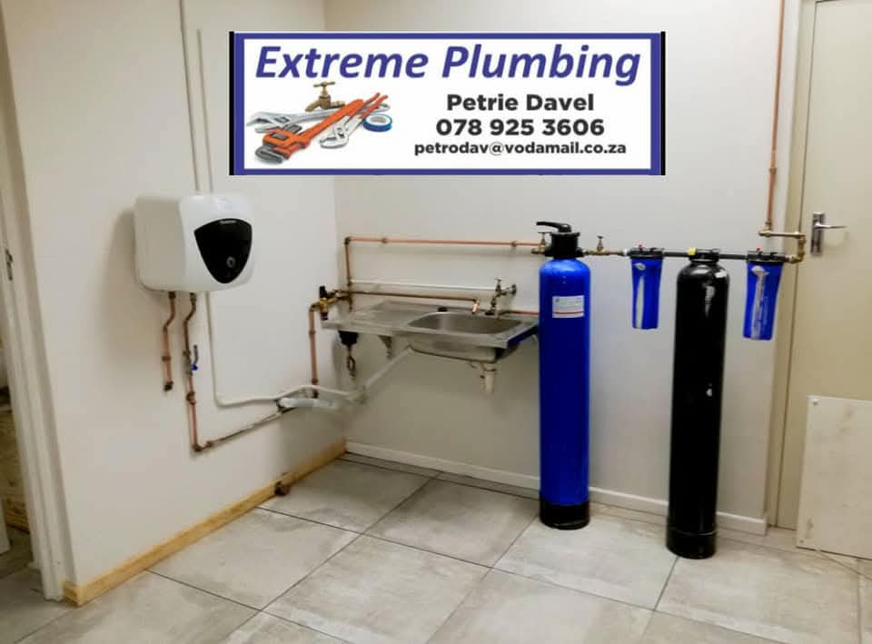 Extreme Plumbing branded sign above water filtration system with blue and black tanks.