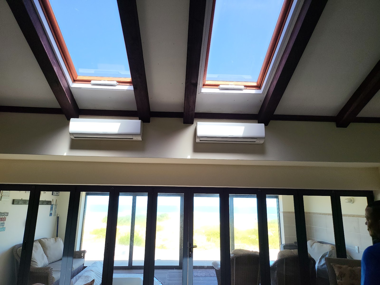Interior skylight installation with two large roof windows and white air conditioning units visible below.
