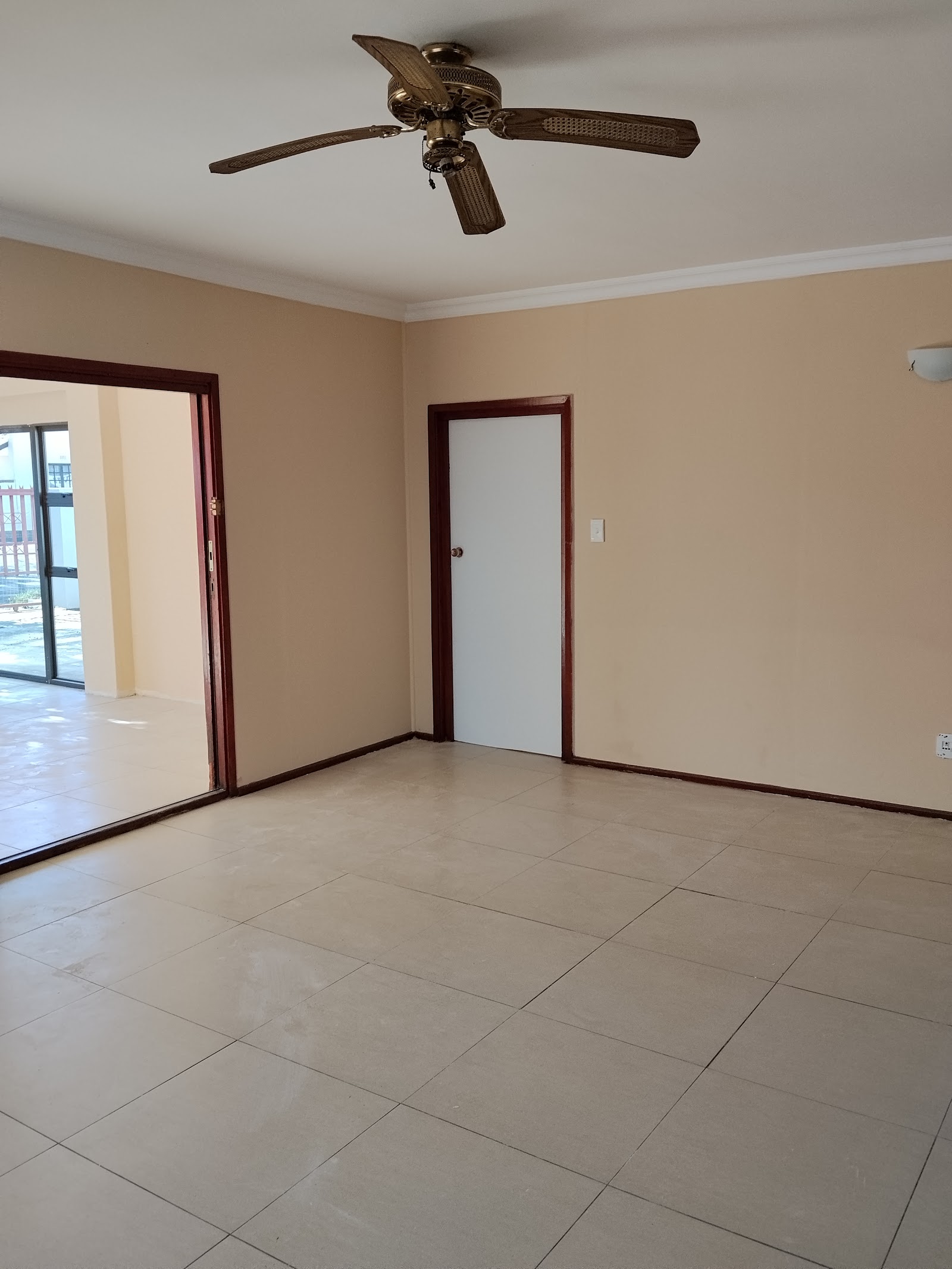 Finished interior room with ceiling fan, tile flooring, dark wood door frames, and glass sliding doors.