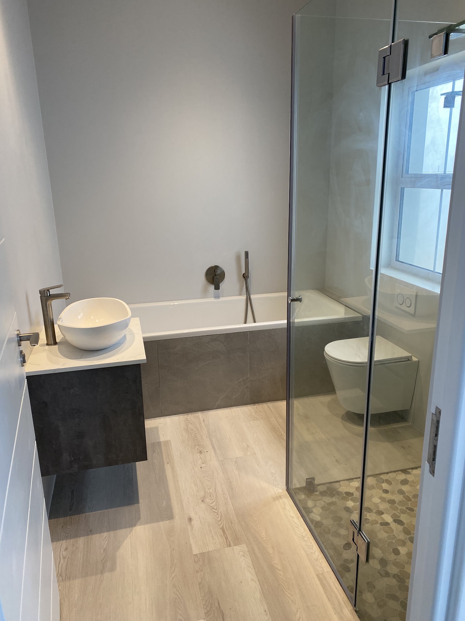 Bathroom renovation featuring soaking tub, walk-in shower with pebble floor, vessel sink, and gray tile accents.