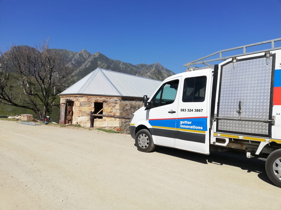 Gutter Innovations service van and truck at rural stone cottage location.