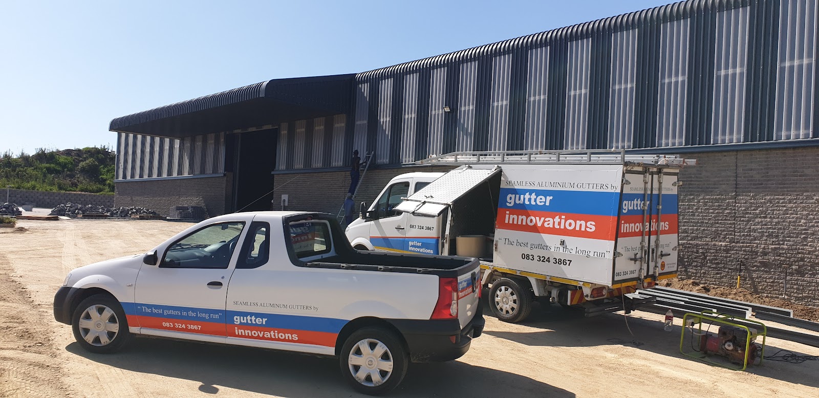 Gutter Innovations branded vehicles and industrial facility with corrugated metal warehouse.