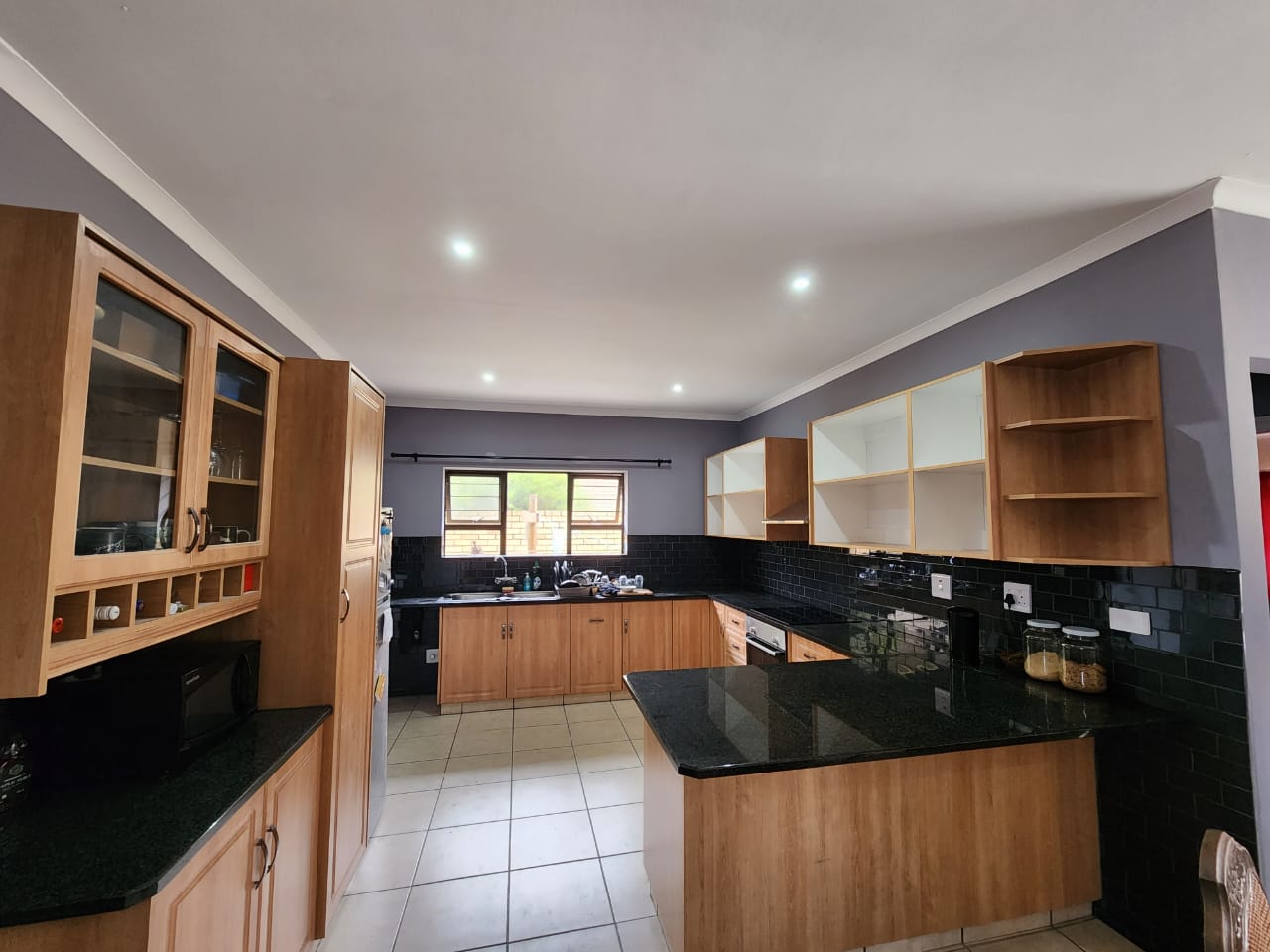 Newly renovated kitchen with wood cabinetry, black granite countertops, and recessed lighting.
