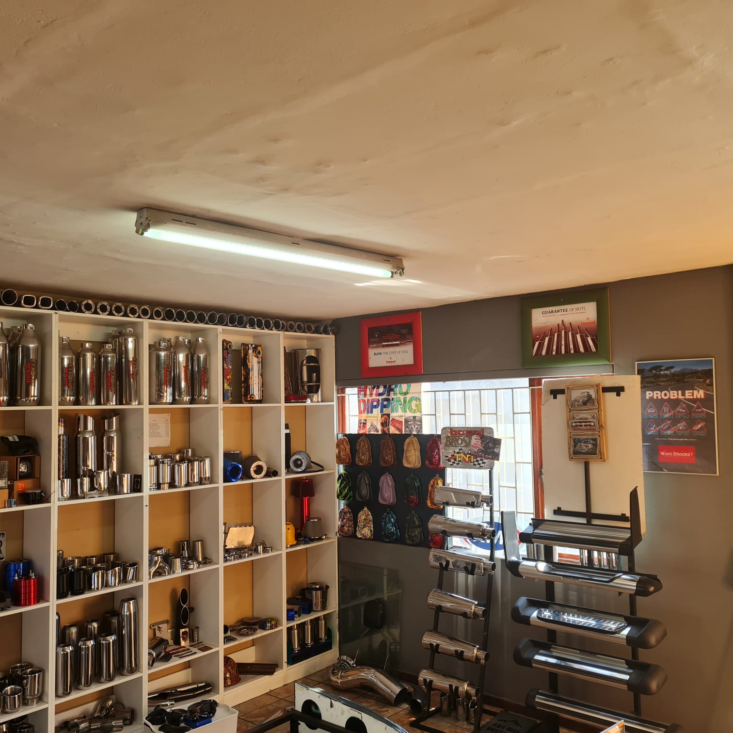 Showroom shelving displaying exhausts, intake filters, branded merchandise and automotive parts.
