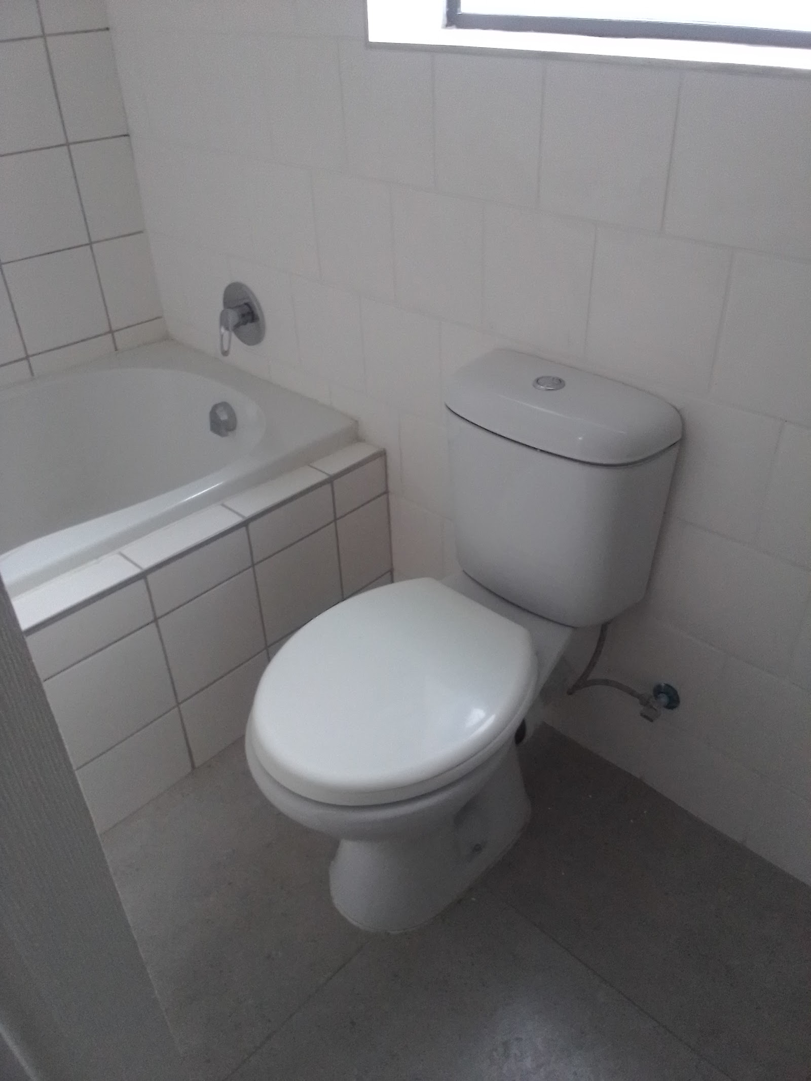 Finished bathroom with white subway tiles, toilet, and bathtub installation work completed.