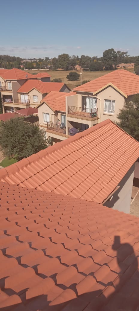 Red clay tile roof installation across multiple residential houses in suburban area.