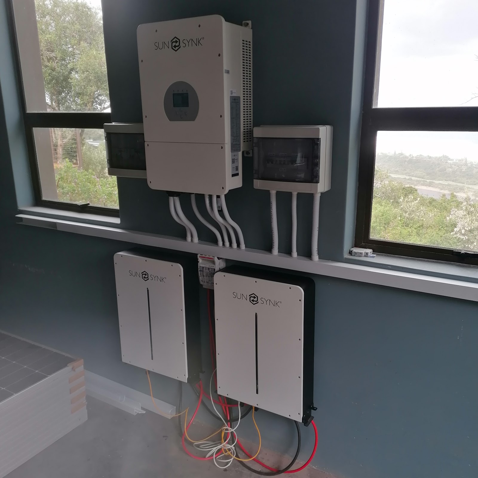 SunSynk inverter and battery storage units installed indoors with cable connections visible.