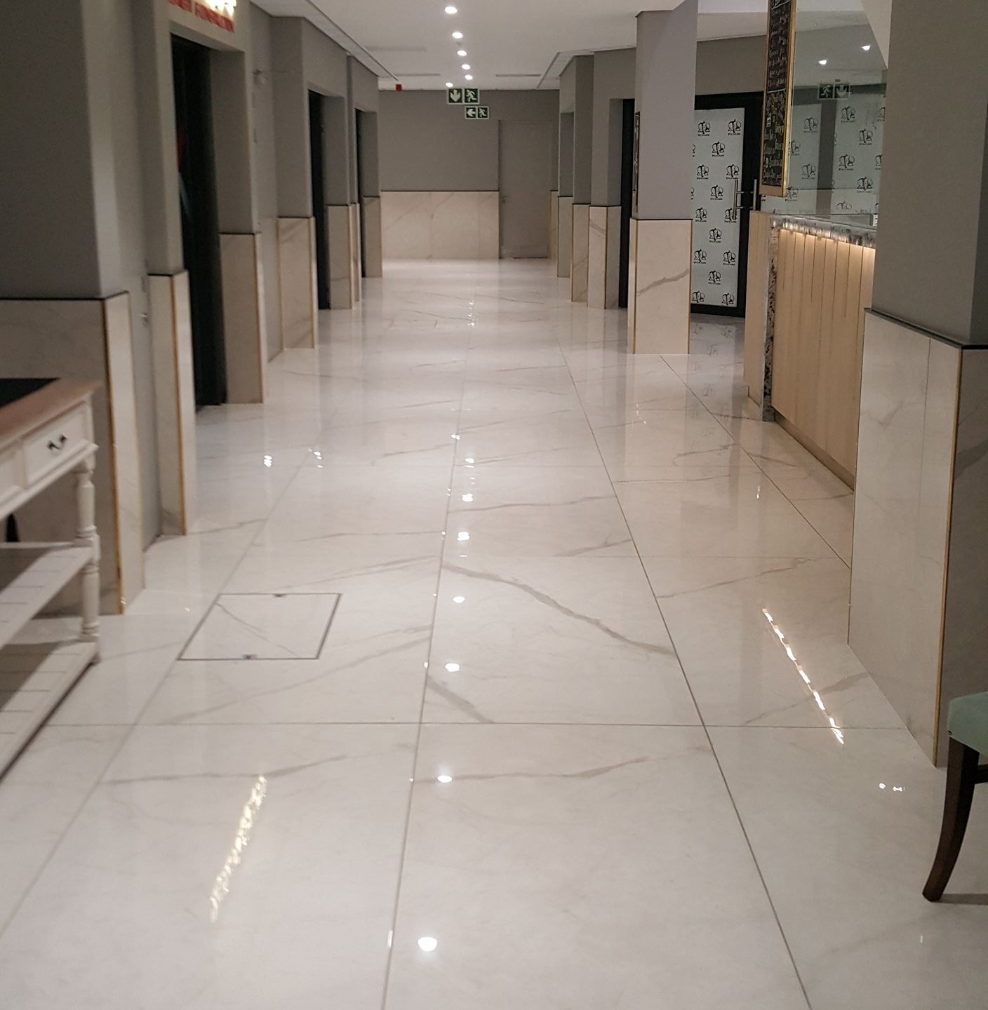 Commercial hallway with polished marble flooring and multiple shop storefronts.