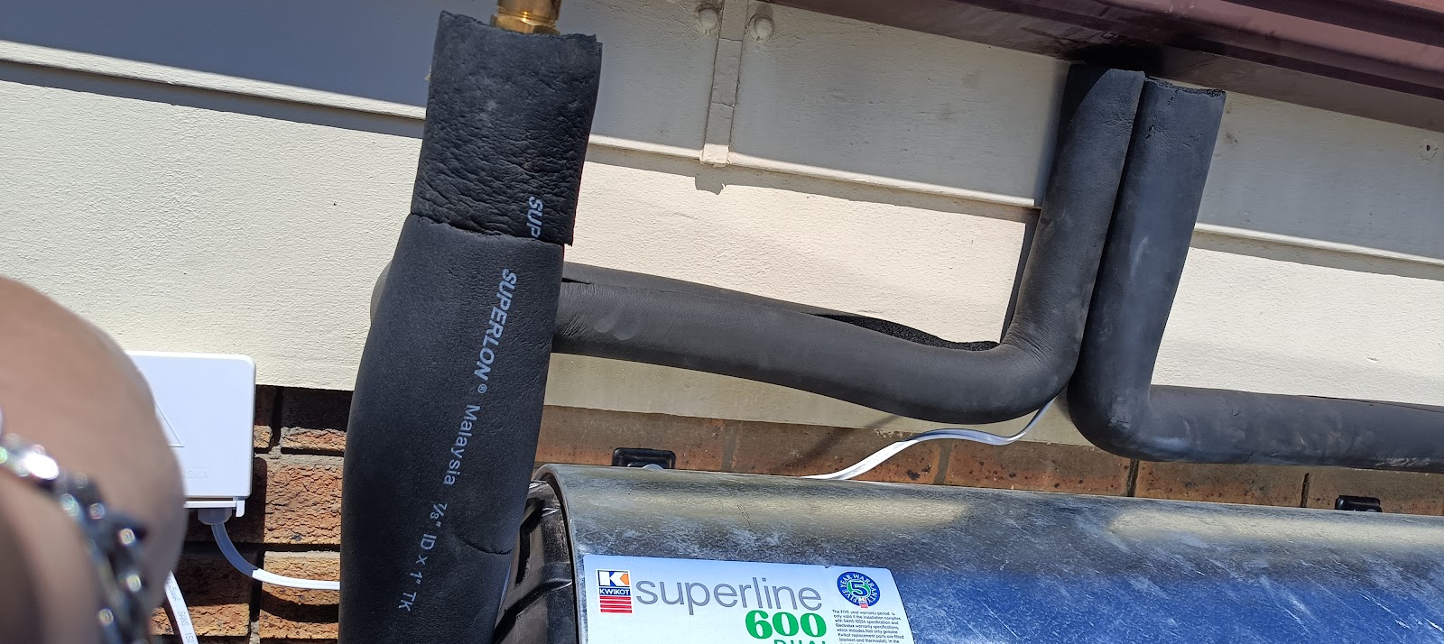 Close-up of Superline 600 water tank with black insulation wrap and copper piping connections.