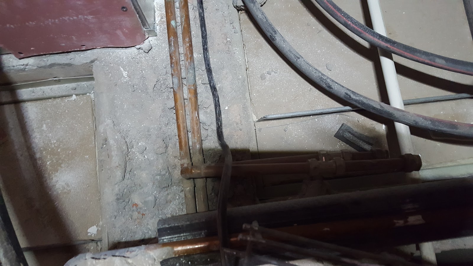 Close-up of boat engine or motor equipment with metal pipes, wiring, and rust-patinated components.
