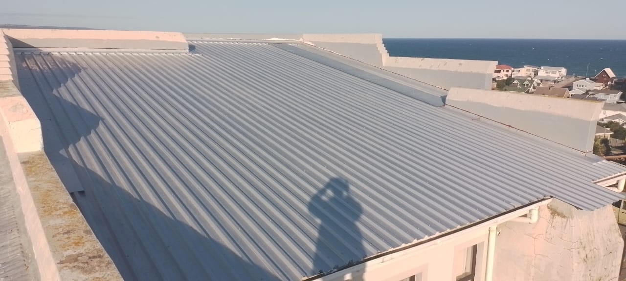 Finished metal standing seam roof overlooking coastal residential area and ocean.