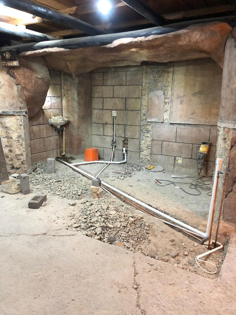 Rough plumbing installation in basement with PVC pipes, copper lines, and supply connections visible.