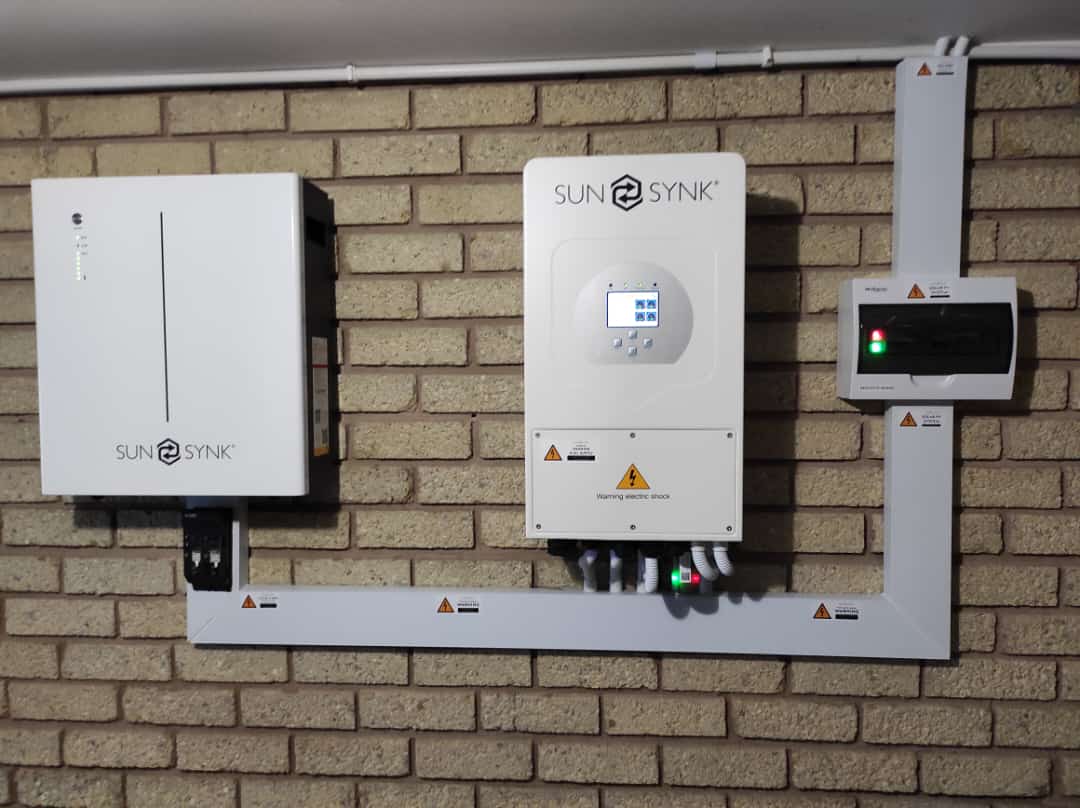 SUN SYNK branded inverter and control system mounted on brick wall with monitoring display.