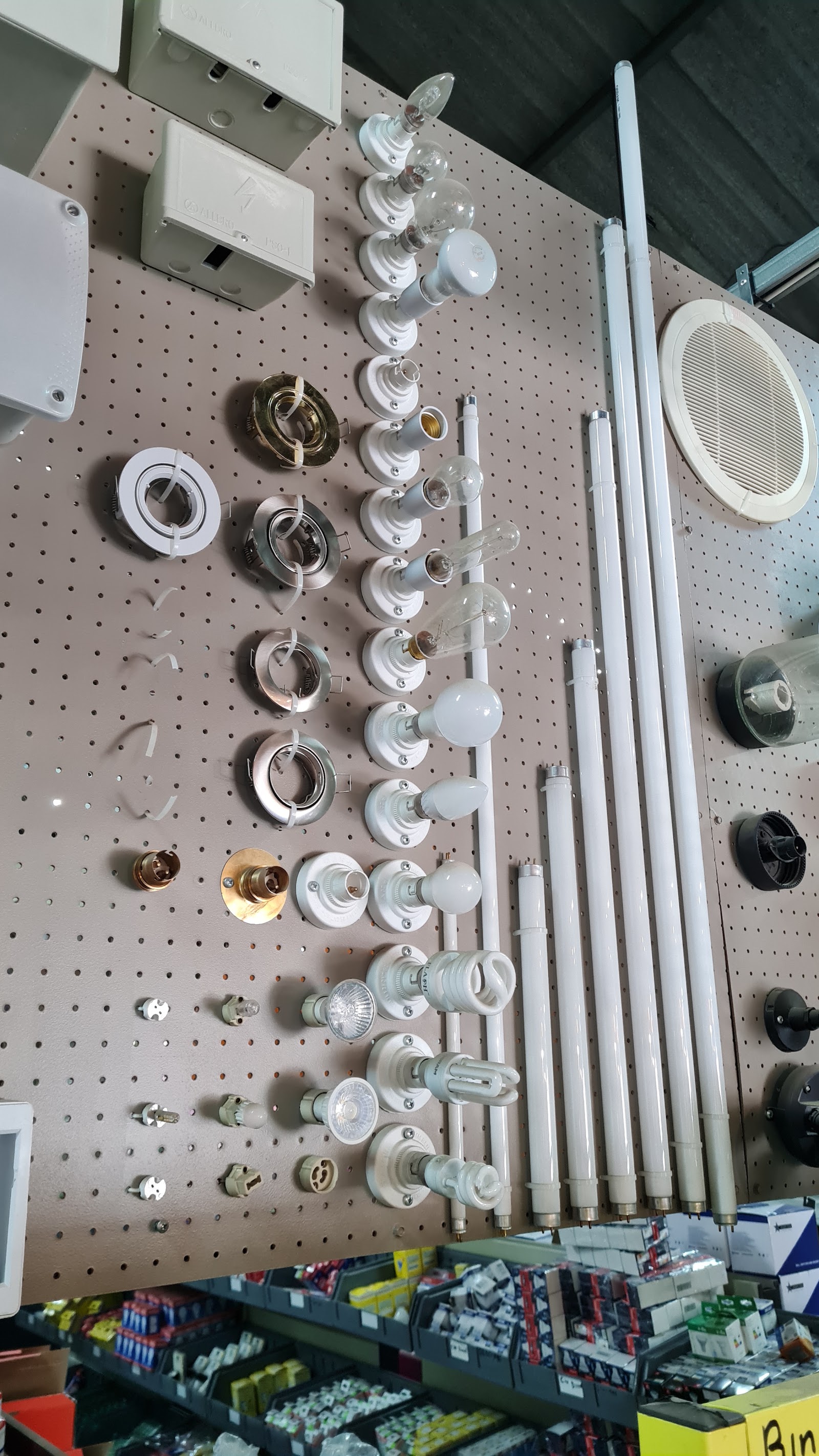 Pegboard display of electrical fixtures including light sockets, switches, outlets, and mounting hardware.