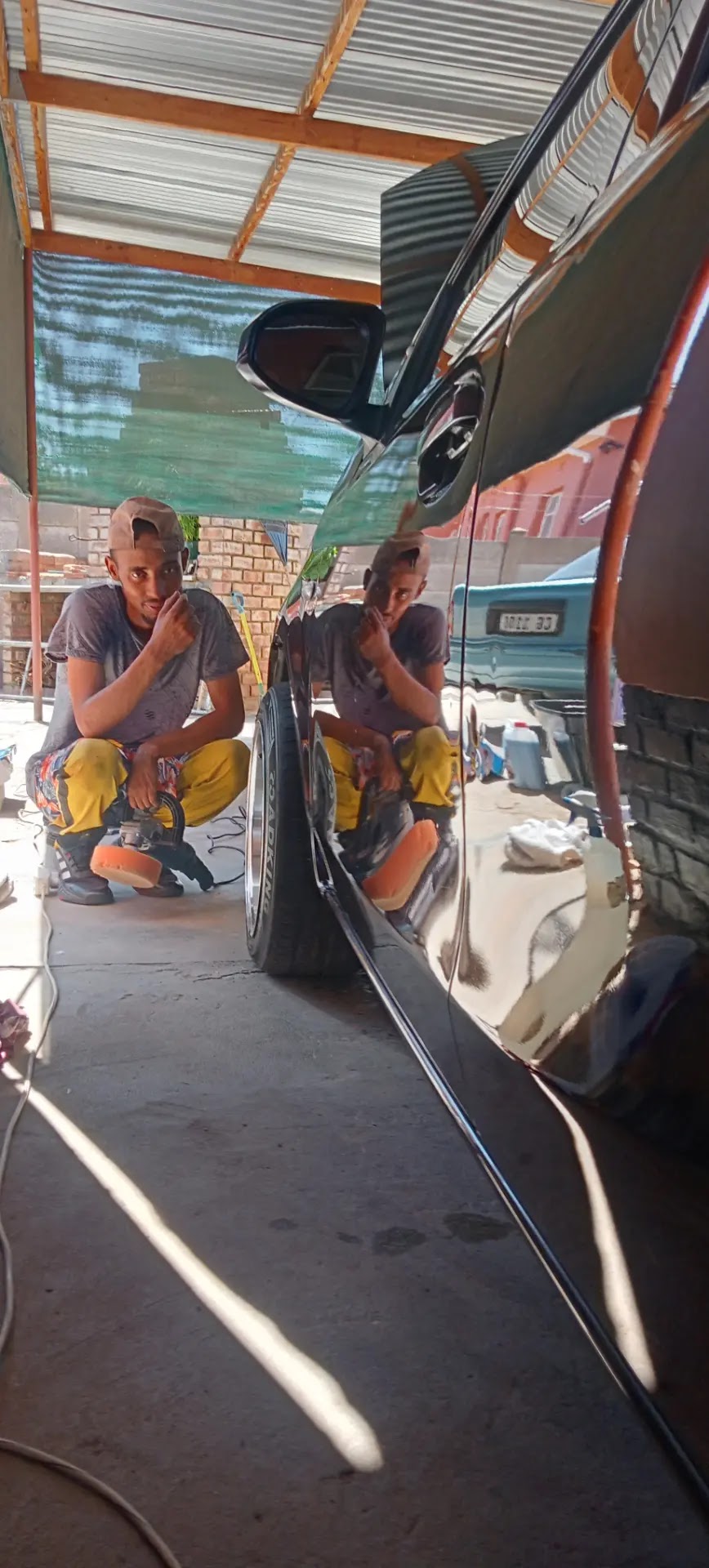 Two male technicians working on white vehicle interior under covered workspace.