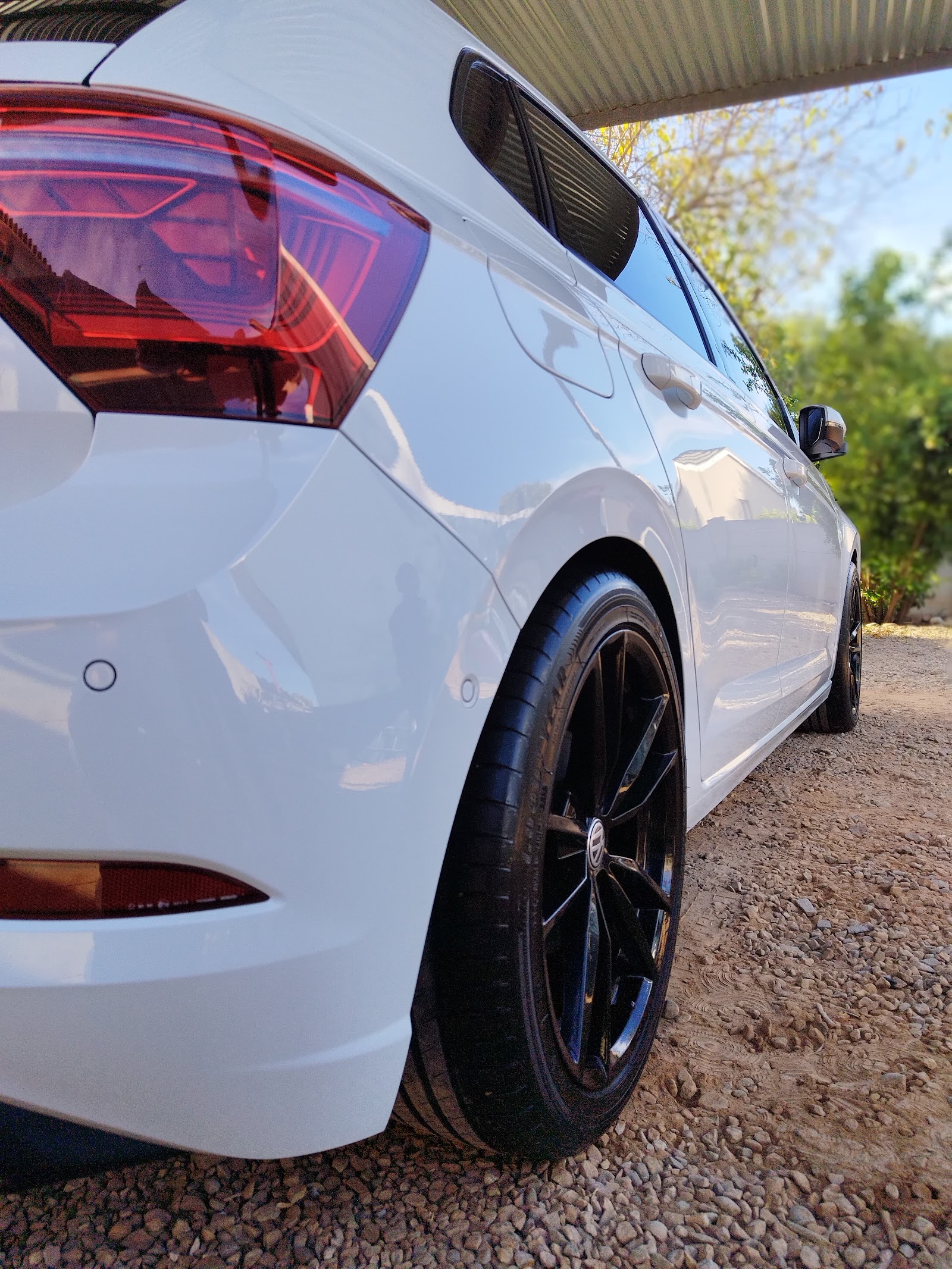 Close-up of white vehicle wheel and taillight detail under covered work area.