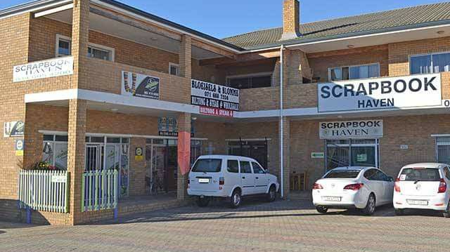 Scrapbook Haven exterior with brick building, multiple parking spaces, white vehicle, clear signage on facade.