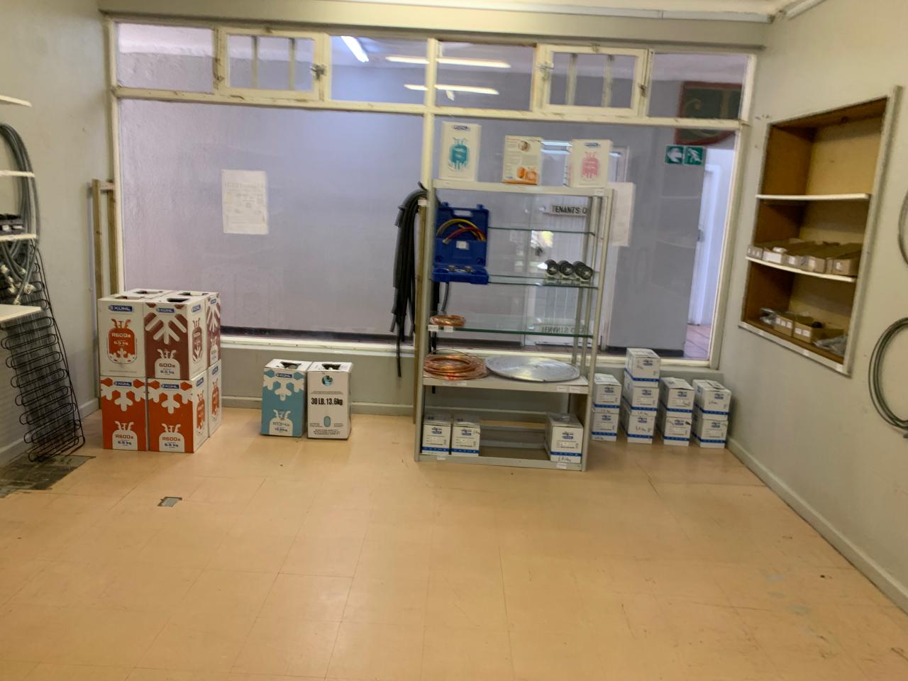 Spare parts inventory shelving displaying refrigeration components, wiring, and appliance accessories in workshop.