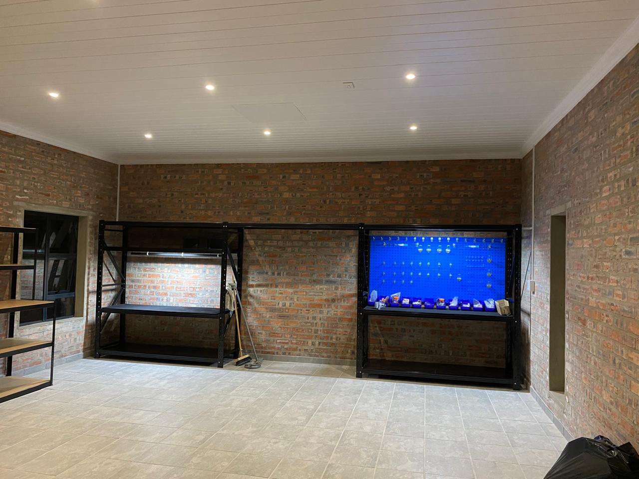 Display cases with blue backing and LED lighting in brick-walled commercial interior space.