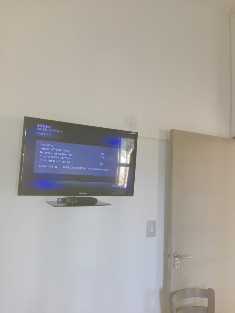 TV installation wizard setup screen displayed on wall-mounted flat-screen television.