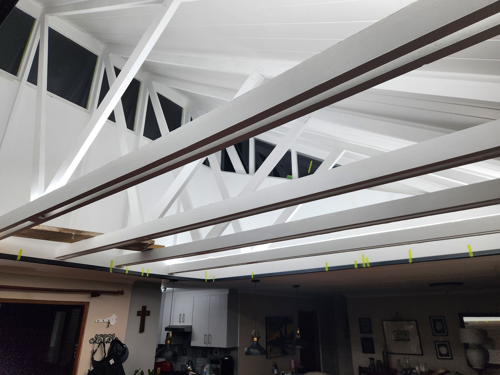 Completed interior ceiling with white drywall, dark structural beams, skylights, and yellow construction markers throughout.